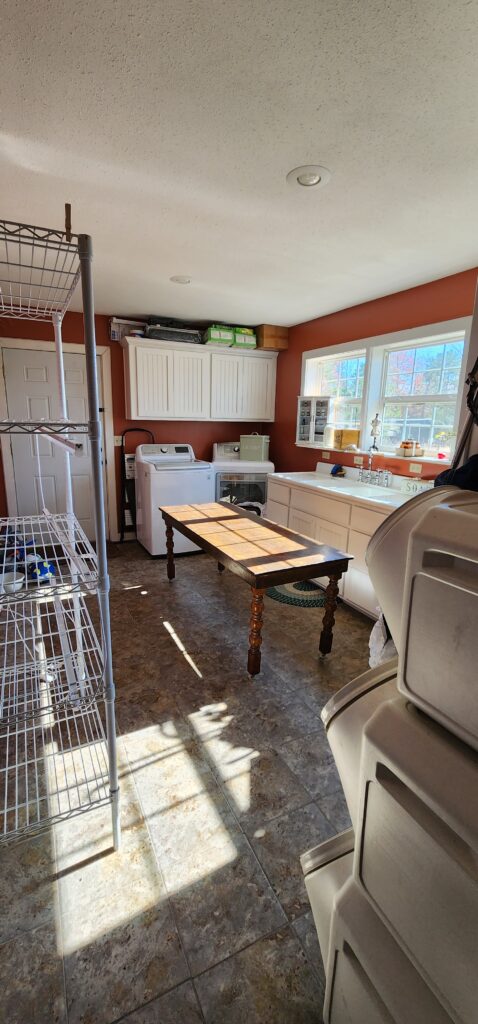 large laundry room before remodel with wine barrel red walls and white cabinets