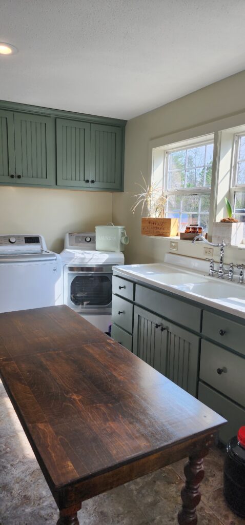 large laundry room with green cabinets and cast iron sink