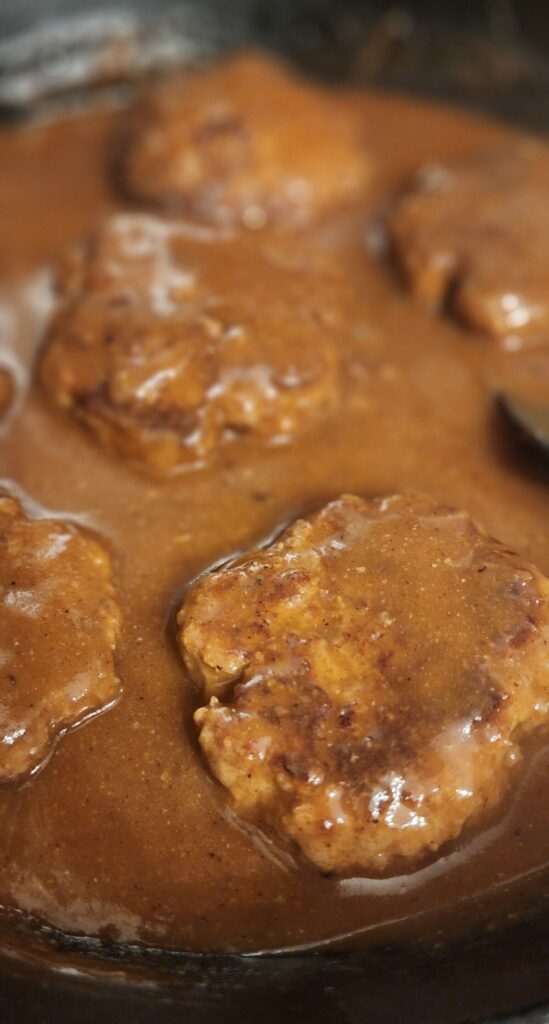 hamburger steaks and gravy in a cast iron pan