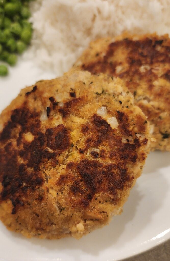 salmon cakes with rice and peas on a plate